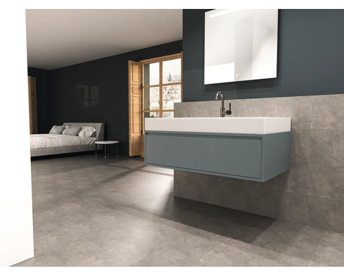 Moderní koupelna s umyvadlovou skříňkou, zrcadlem a postelí v pozadí.