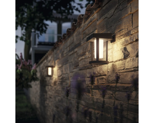 Dvě venkovní nástěnné lampy na kamenné zdi osvětlují venkovní prostor.
