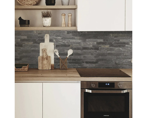 Pohled na kuchyň s pracovní deskou, kamennou stěnou a vestavnou troubou