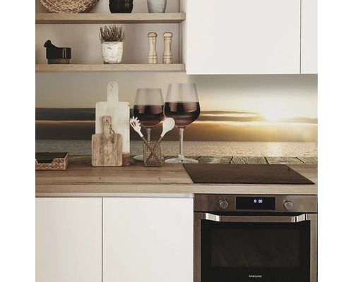 Kuchyňská scéna s ochrannou stěnou proti stříkající vodě, dvě sklenice vína a kuchyňské náčiní na pracovní desce