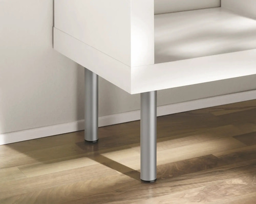 Detail bílého nábytku se stříbrnými nohami na dřevěné podlaze