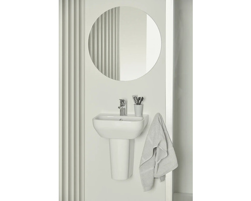 Koupelna s umyvadlem na desku, baterií, kulatým zrcadlem a ručníkem