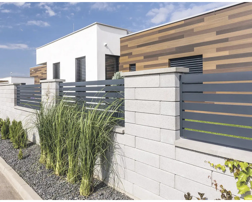 Moderní zahradní plot s betonovými sloupky a horizontálními plotovými prvky před rodinným domem.