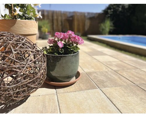 Terasa s květináči, dekorační koulí a bazénem v pozadí