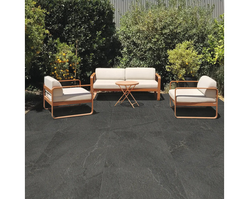 Terasa s posezením a tmavými podlahovými dlaždicemi ve venkovním prostoru.