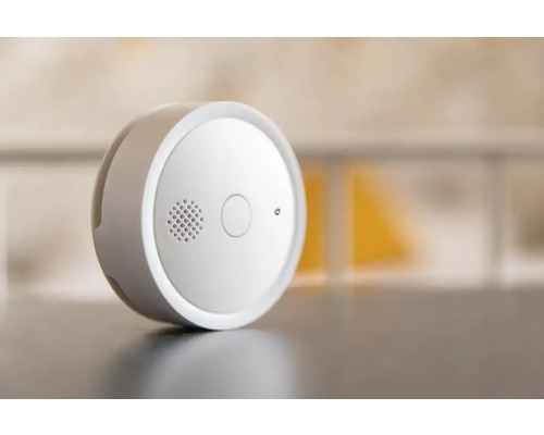 Kruhový hlásič kouře s testovacím tlačítkem a mřížkou reproduktoru.