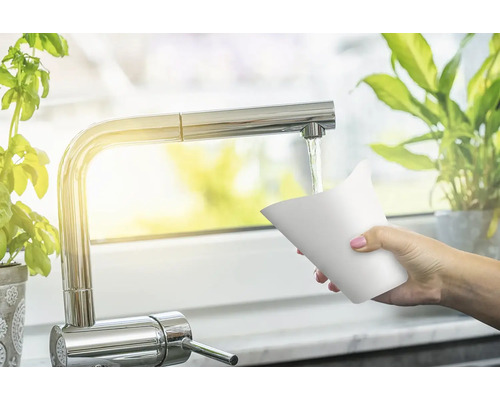 Žena drží šálek pod kuchyňským kohoutkem