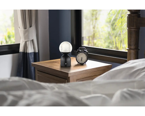 Dekorativní noční lampa vedle budíku na nočním stolku