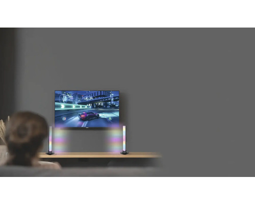 Osoba sleduje televizi se dvěma LED světelnými lištami na stole