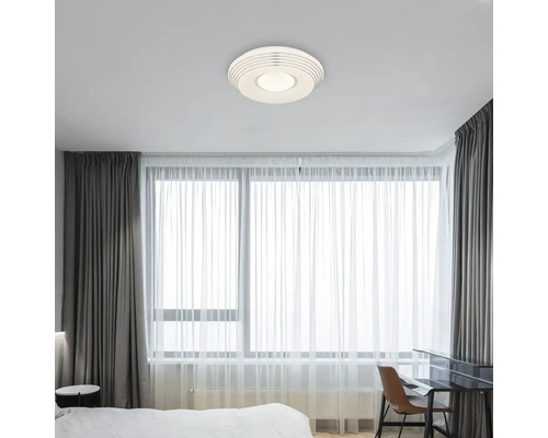 Moderní ložnice s kulatým stropním svítidlem a závěsy