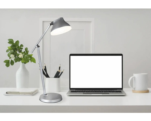 Pracovní prostor se stolní lampou, notebookem a kancelářskými potřebami
