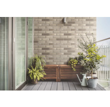 Balkon s kamennou stěnou, dřevěnou podlahou a rostlinami