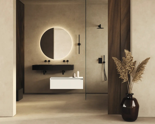 Koupelna s kulatým zrcadlem, černým umyvadlem, bílou spodní skříňkou a sprchou.