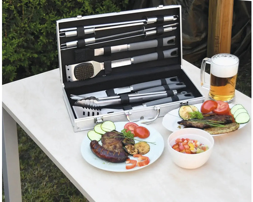 Sada grilovacího náčiní v kufříku s připraveným jídlem a sklenicí piva na stole