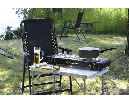 Venkovní scéna s kempingovým stolem, plynovým sporákem a židlí