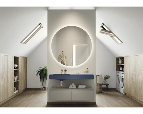 Světlá podkrovní koupelna s kulatým zrcadlem s osvětlením, umyvadlem, pračkou a vestavěnými skříněmi
