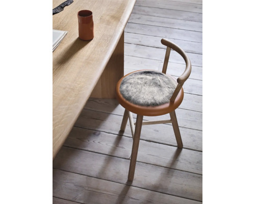 Dřevěná židle s kožešinovým polštářem u stolu