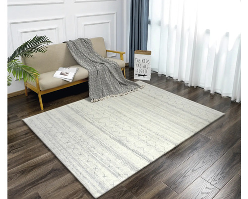 Obývací pokoj s pohovkou, dekorativním polštářem a vzorovaným kobercem na dřevěné podlaze.