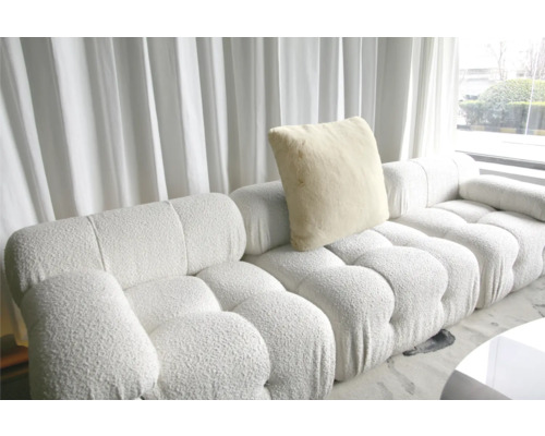 Modulární pohovka s polštářem před oknem se závěsy