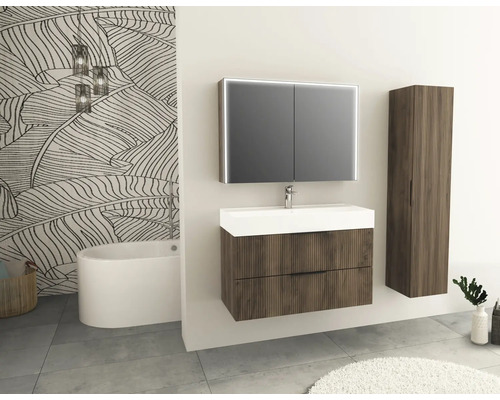 Koupelna s umyvadlem, zrcadlovou skříňkou, vysokou skříňkou a vanou před vzorovanou tapetou