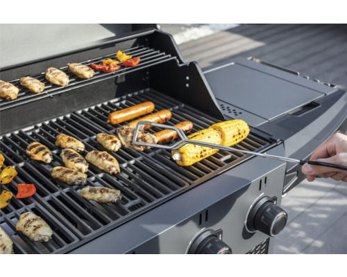 Plynový gril s kuřecími křídly, klobásami a kukuřičnými klasy na grilovací mřížce