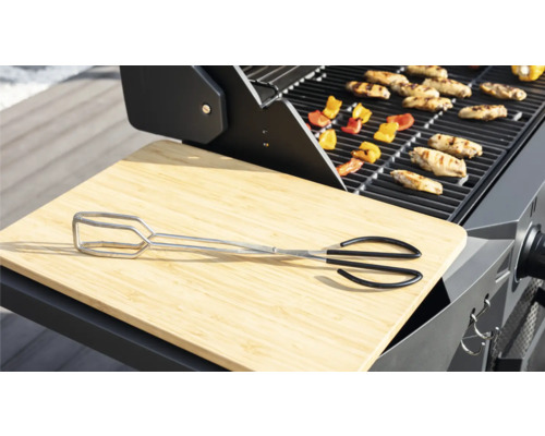 Grilovací scéna s grilovacími kleštěmi, prkénkem na krájení, grilovanými potravinami