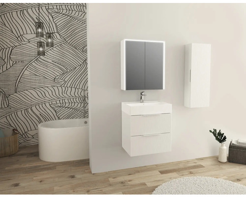 Světlá koupelna s umyvadlem, zrcadlovou skříňkou, závěsnou skříňkou a vanou před stěnou se vzorem listů.