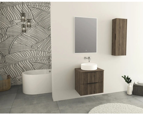 Moderní koupelna s umyvadlem, zrcadlem, závěsnou skříňkou a volně stojící vanou před stěnou s tapetou s motivem listů