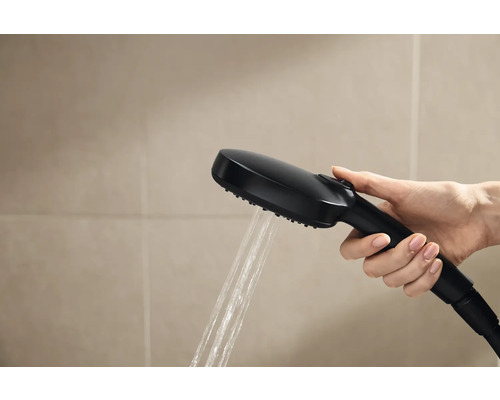 Ruka drží černou sprchovou hlavici s tekoucí vodou