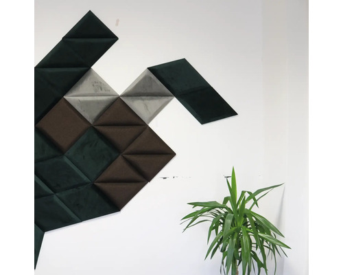 Nástěnné panely trojúhelníkového tvaru v různých odstínech na zdi, vedle nich pokojová rostlina.