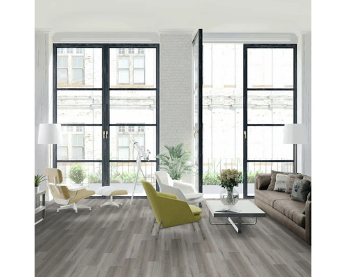 Světlý obývací pokoj se šedou podlahou, pohovkou a křesly před velkými okny