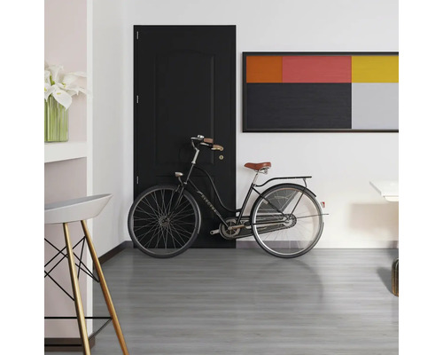 Scéna s černými dveřmi, kolem a uměleckým dílem na světlé stěně