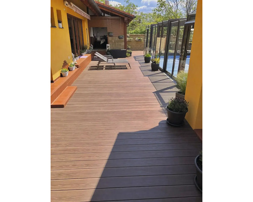 Terasa se světle hnědými a tmavě hnědými terasovými prkny, lehátko a rostliny