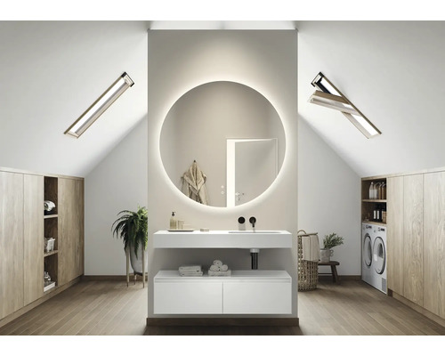 Světlá koupelna v podkroví s umyvadlem, kulatým zrcadlem s osvětlením, střešními okny a pračkou.