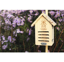 Dřevěný hmyzí hotel s designem berušky před květinami