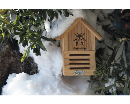 Dřevěný domeček pro berušky s dekorací na zahradě