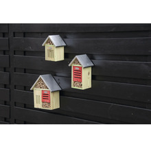 Tři dřevěné hotely pro hmyz s kovovou střechou na plotě