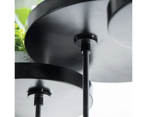 Detailní záběr černého, vícepatrového stojanu na rostliny s kulatými policemi a závitovými tyčemi.