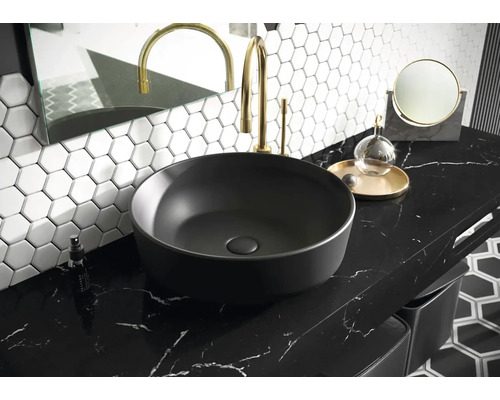 Umyvadlo na pracovní desce v koupelně s baterií, zrcadlem a šestiúhelníkovými dlaždicemi