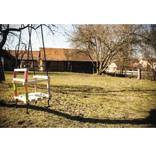 Dřevěná houpačka s barevnými akcenty v zahradě