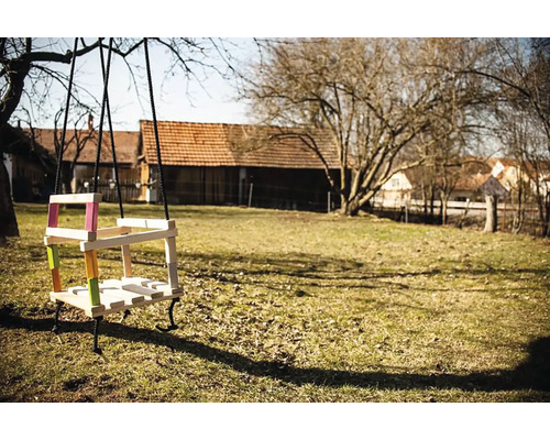 Dřevěná houpačka s barevnými akcenty v zahradě