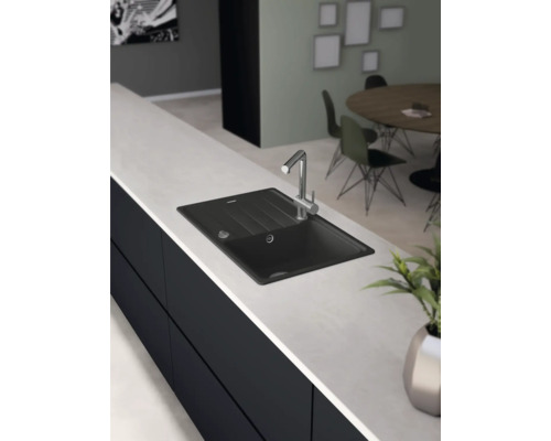 Černý dřez s vodovodní baterií na kuchyňské lince.