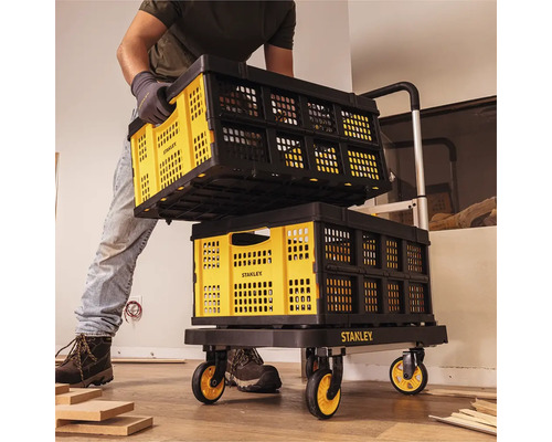 Muž přepravuje skládací přepravky Stanley na vozíku