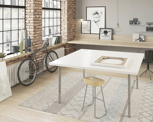 Ateliér s bílým stolem, stoličkou a kobercem před cihlovou zdí