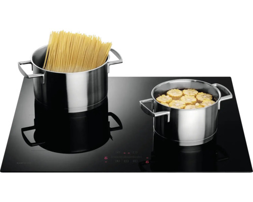 Černá indukční varná deska s hrnci s těstovinami a kukuřicí