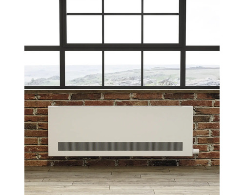 Deskový radiátor před cihlovou stěnou pod oknem