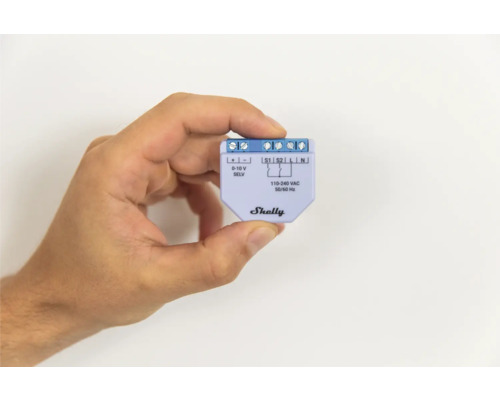 Ruka drží stmívač Shelly pro chytrou domácnost