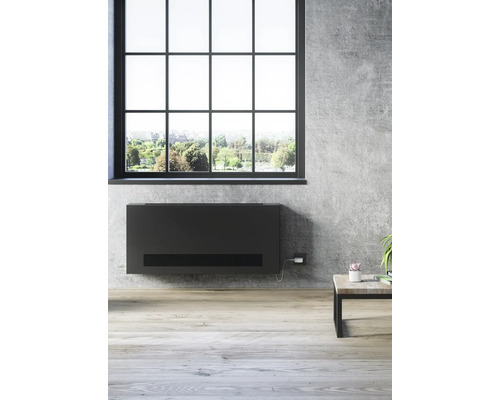 Místnost s oknem a plochým radiátorem na stěně.