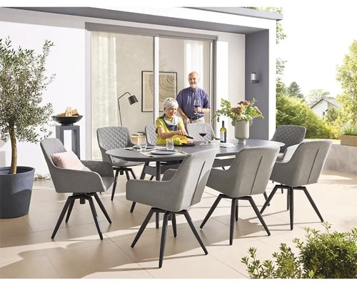 Velká terasa se zakulaceným kamenným jídelním stolem obklopeným osmi židlemi s područkami