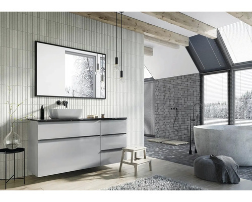 Světlá koupelna s umyvadlem, zrcadlem, vanou a mozaikovými obklady na zdi.